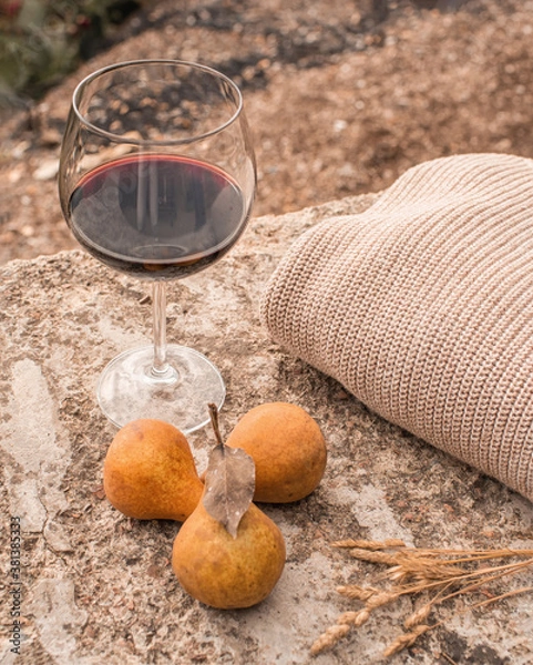 Fototapeta Still-life with a glass of red wine, three autumn yellow pears and beige trendy warm sweater. Trendy autumn concept in pastel colors. Autumn mood in rustic style.
