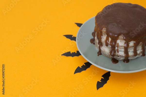 Obraz Chocolate cake with streams on orange background. Bats under a plate. Halloween concept, trick or treat. Handmade cooking. Brownies with cream. Copy space, flat lay. Selective focus, blur.