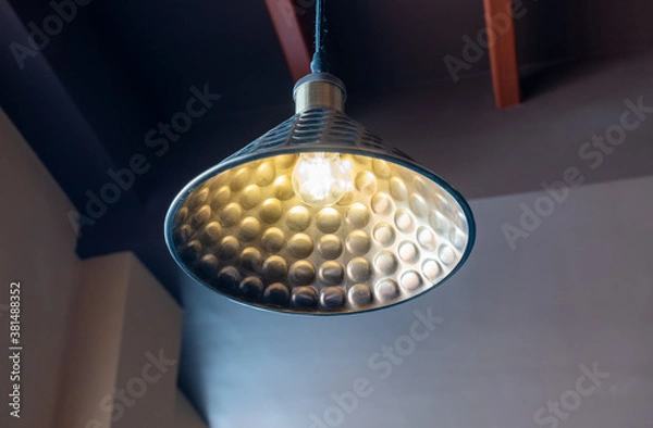 Fototapeta An old round bronze lamp with an electric bulb suspended from the ceiling