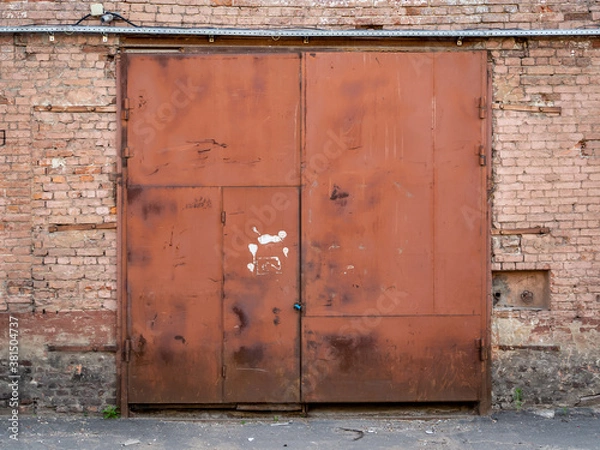 Fototapeta Rusty gate in an old brick warehouse. Old building. Texture, background