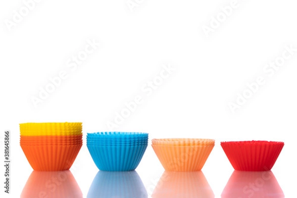 Fototapeta multicolored small silicone cupcake molds reflected in glass table surface isolated on white background copy space. Cooking of homemade baked goods, cakes. Home cooking concept.