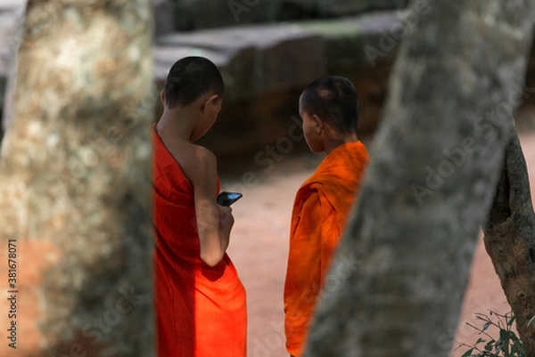 Fototapeta Focusing on unidentified two monks is using the mobile phone at Ta Prohm Temple, Siem Reap, Cambodia.