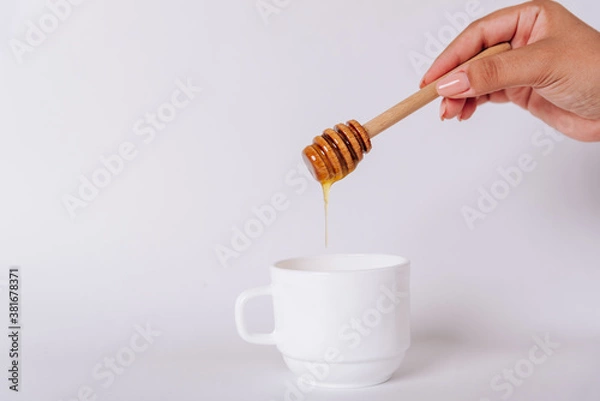Obraz The girl's hand holds a Honey Dipper on a white Cup