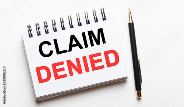 Fototapeta CLAIM DENIED written in a white notepad near a pen on a light background. Legal concept