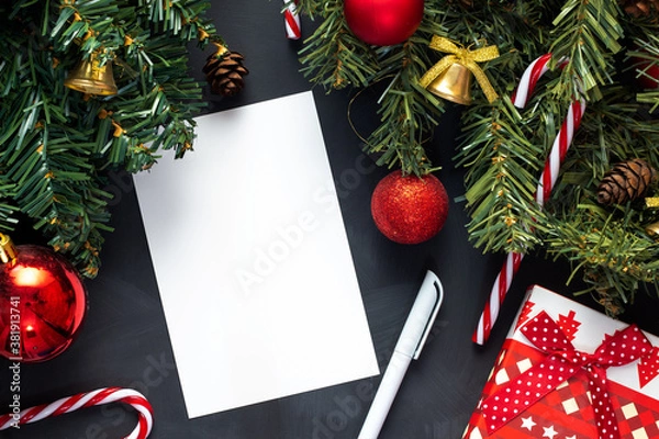 Obraz A list of Christmas gifts lies on a black table next to a decorated Christmas tree.