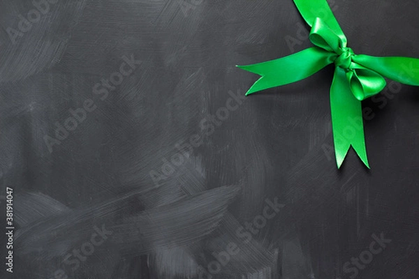 Obraz Green bow in the upper right corner of the dark background.