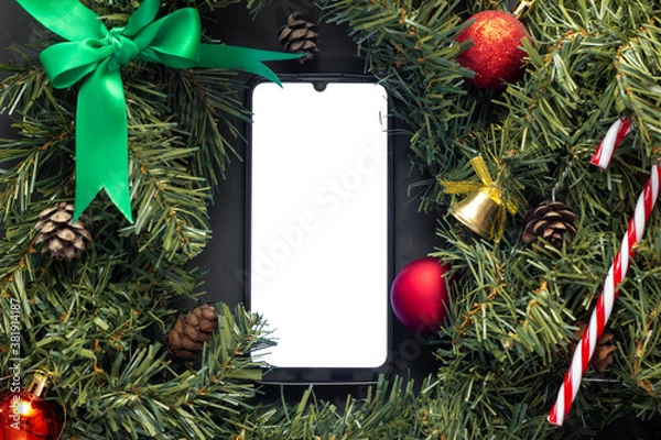 Obraz Smartphone with screen on lies in the middle of Christmas decorations.
