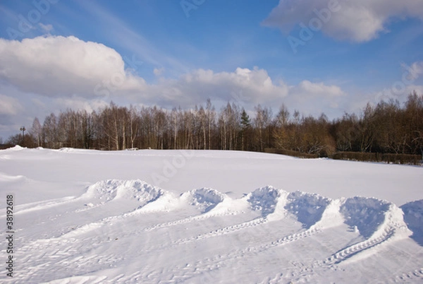 Fototapeta Snow pushed into piles in the park winter backdrop