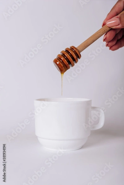 Obraz The girl's hand holds a Honey Dipper on a white Cup