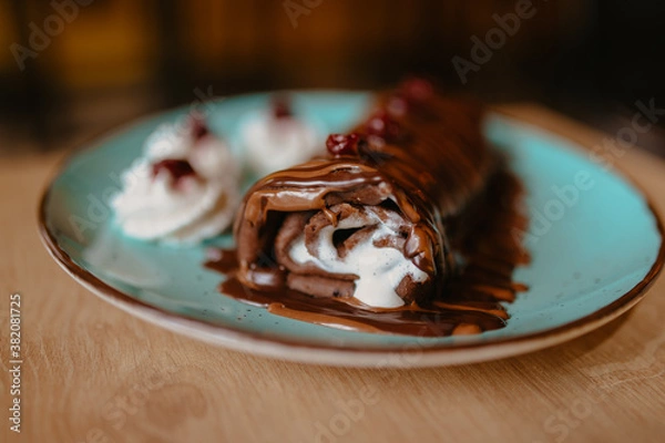 Fototapeta chocolate pancake with bananas, nuts and chocolate sauce. the toning. selective focus. a rolled chocolate pancake is a calorie bomb
