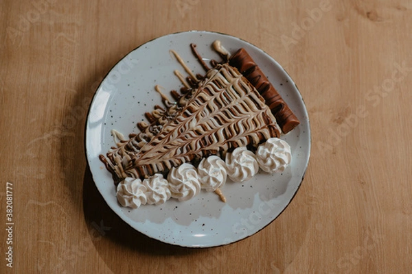 Fototapeta chocolate pancake with bananas, nuts and chocolate sauce. the toning. selective focus. a rolled chocolate pancake is a calorie bomb