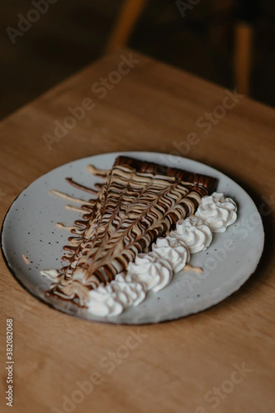 Fototapeta chocolate pancake with bananas, nuts and chocolate sauce. the toning. selective focus. a rolled chocolate pancake is a calorie bomb