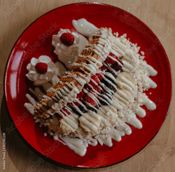 Fototapeta chocolate pancake with bananas, nuts and chocolate sauce. the toning. selective focus. a rolled chocolate pancake is a calorie bomb