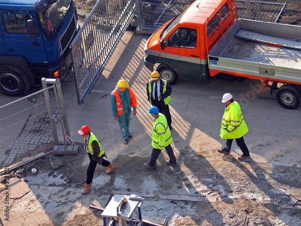 Fototapeta Constructionworkers with cars walking on a buildingplace