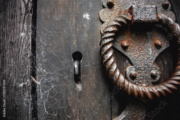 Fototapeta Old rusty handle and keyhole on an old church door with spider webs.