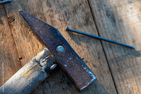 Fototapeta Old vintage hammer and nails on a wooden background, close-up, selective focus.