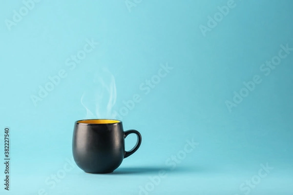 Obraz Black and yellow matte ceramic mug casting a shadow on a bright blue background