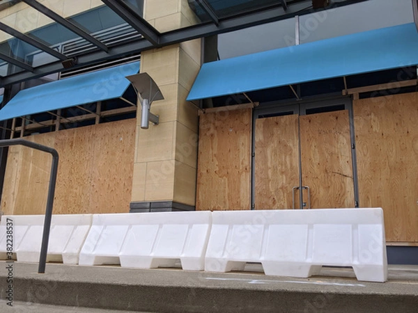 Fototapeta boarded up windows and doors in a downtown building during protests and riots