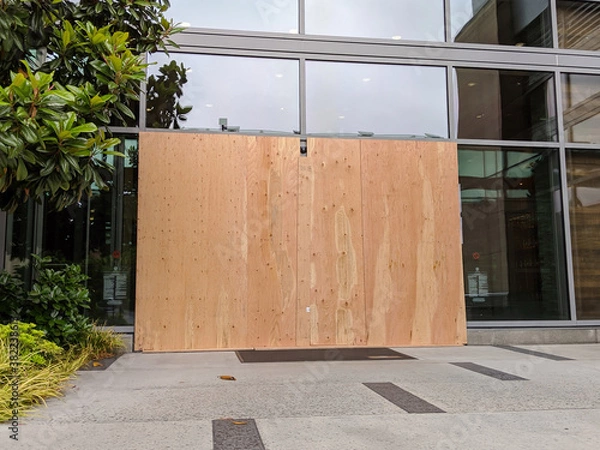 Fototapeta boarded up windows and doors in a downtown building during protests and riots