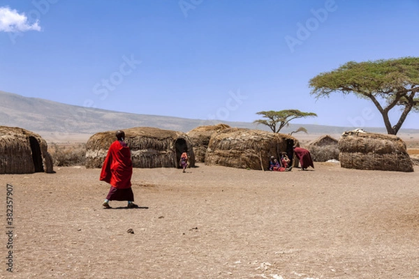 Obraz Massai villagers with their daily life inside an Massai village with traditional huts in the Serengeti National Park. Massai tribes live in the natural reserve regions in Tanzania.