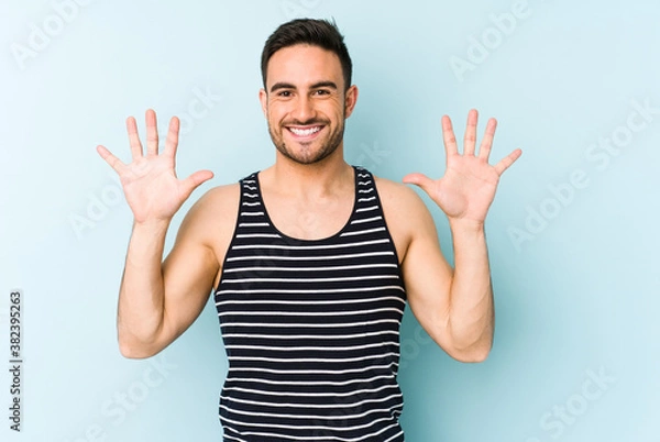 Obraz Young caucasian man isolated on blue background showing number ten with hands.