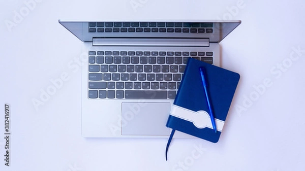 Fototapeta Light gray laptop with notebook and pen on a white background. 
Silver ultrabook top view