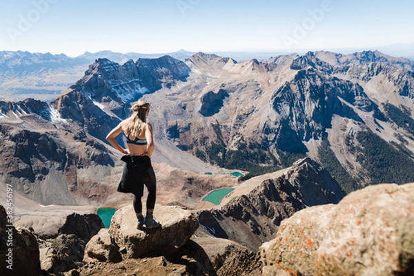 Fototapeta A woman standing at the summit of Mount Sneffles enjoying the view of the Blue Lakes. 