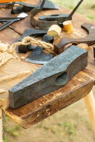 Fototapeta iron head of a hammer A large construction tool lies on a table against the background of an ax. selective focus