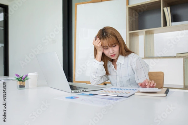 Fototapeta Young Business women are stressing about numbers with calculator and laptop at office ,a stress-to-work concept.