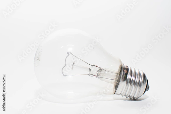 Fototapeta an outdated incandescent lamp with a base lies on a white background. isolate light bulb