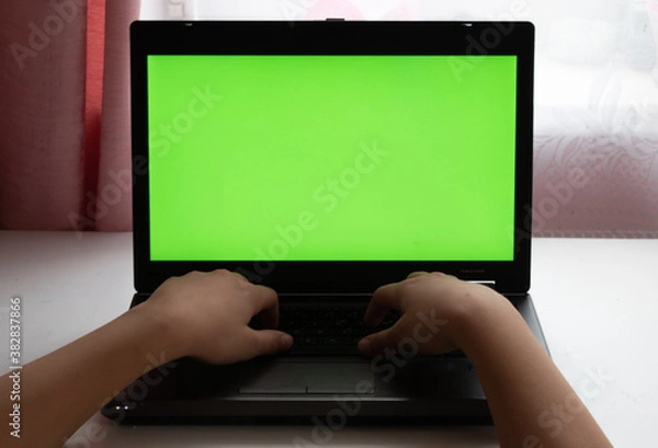 Fototapeta Laptop with green screen. With fingers on the keyboard. Gaming. Playing. Location - Limbazi, Limbazu novads, Latvia. Shoot date - 10/04/2020.