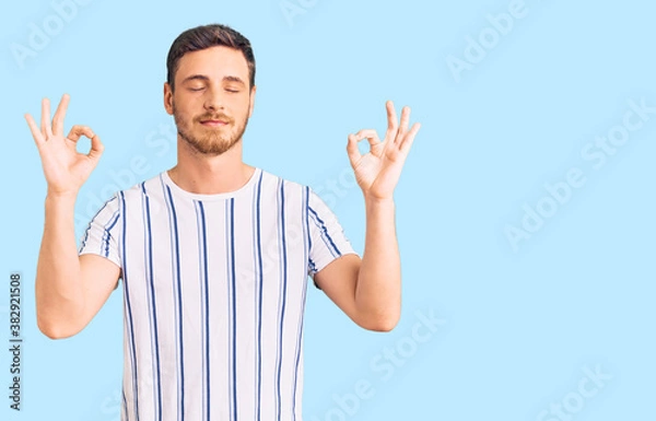 Obraz Handsome young man with bear wearing casual clothes relax and smiling with eyes closed doing meditation gesture with fingers. yoga concept.