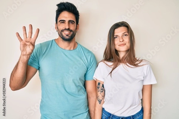 Fototapeta Beautiful young couple of boyfriend and girlfriend together showing and pointing up with fingers number four while smiling confident and happy.