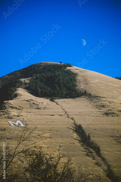 Fototapeta Moon with Mount Sentinel also features the hillside letter "M", originally known as "Mount Woody,"is a small mountain located immediately east of the University of Montana in Missoula, Montana. 