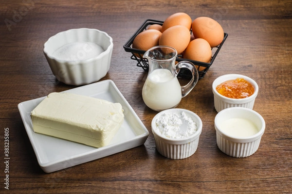 Obraz Ingredients for making cheesecake. Fresh chicken eggs, sugar, milk, flour, cream, cheese, jam. On a wood table top background.