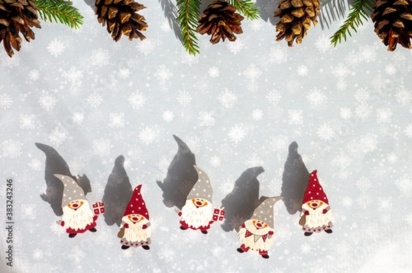 Obraz a frame of little wooden scandinavian gnomes and pine cones, christmas card with snowy background and cute elves in red and grey hats, copy space