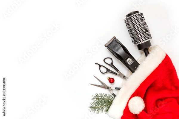 Fototapeta Christmas composition. Hairdressing tools in a Santa Claus hat on a white background. Template for a postcard or information about a hair salon. Flat lay, copy space.