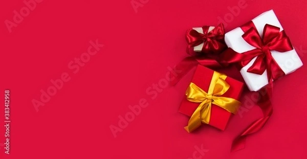 Fototapeta Christmas gift boxes with red and gold ribbons on a red banner background. Christmas and new year banner. Flat lay, top view, copy space, banner