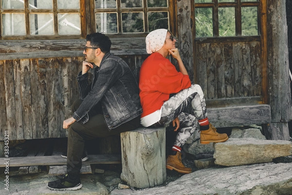 Fototapeta Couple sitting back to back in front of the house. Two sulky adults turned away from each other.