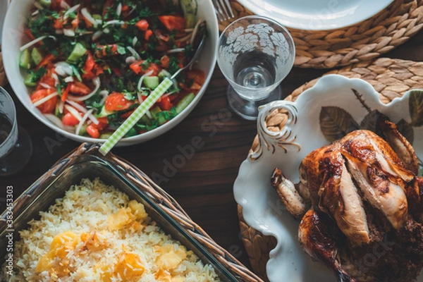 Fototapeta Whole roasted chicken with rice and salad served on the table.