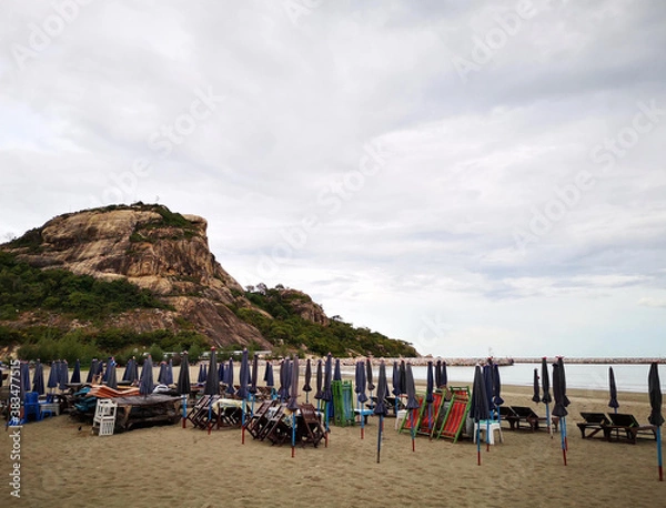 Fototapeta Foldable beach umbrellas and beach chairs await visitors.