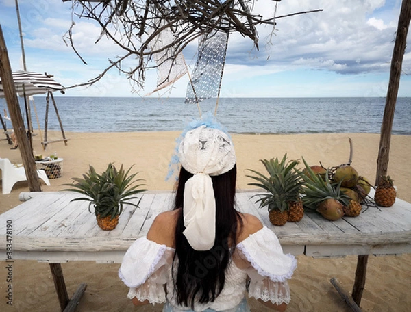 Fototapeta Woman with fruit table, pineapple, coconut by the beach, get the sea breeze and sunshine