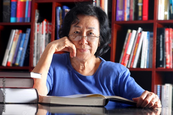 Obraz Senior student reading a book at the library