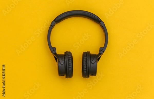 Fototapeta Wireless stereo headphones on yellow background. Top view