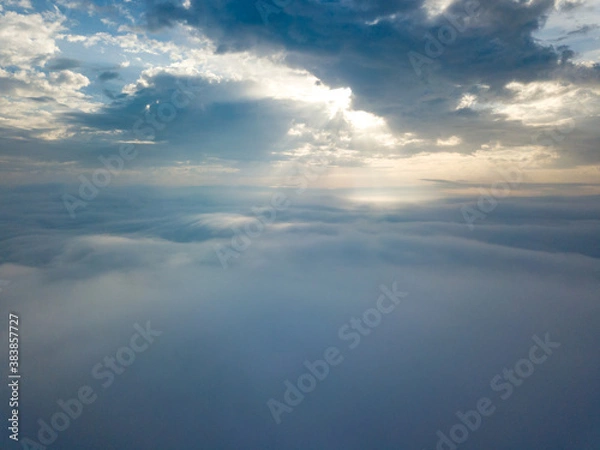 Fototapeta Aerial drone flight over the fog. There are thick clouds of fog below, the sun breaks through the clouds.