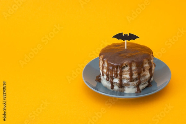 Obraz Bat of paper on a stick. Happy halloween concept, trick or treat. Cake with streams, decoration sweets for the holiday. ?elebration for horror. Orange background, copy space for text at left.