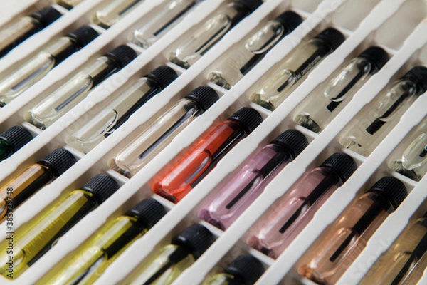 Fototapeta Sample of colored perfume bottles with different types of fragrances and aromas in a makeup case on the table. Beauty concept. Feminine concept. Colorful concept.