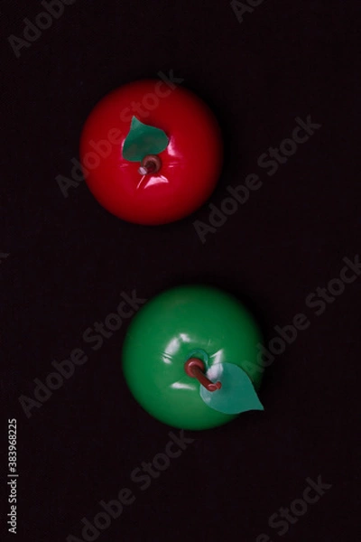Fototapeta Red and green apple on a dark background. Plastic toy