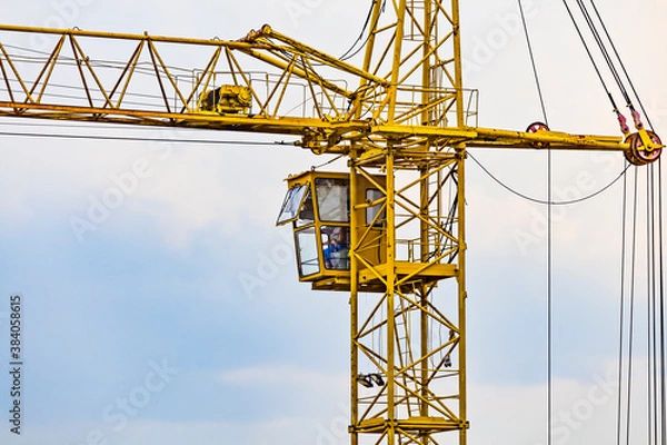 Obraz Partial view of a yellow tower construction crane - Operating cabin with operator inside it.