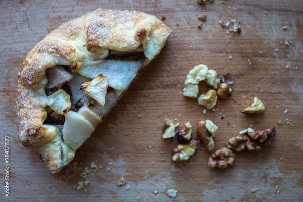 Fototapeta a piece of pie with pear and nuts on a wooden plank